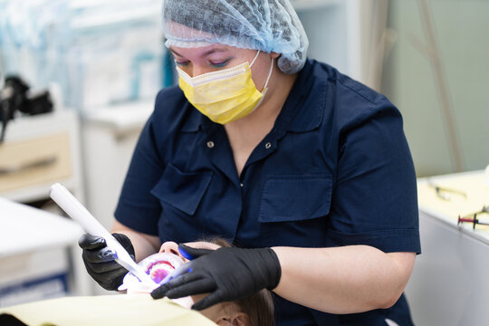 Dentist Performing Dental Treatment with UV Light in Clinic
