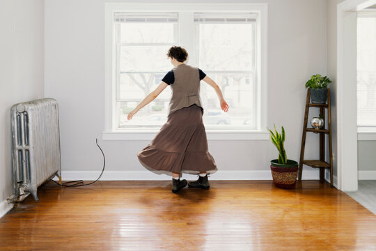 Anonymous woman spinning in new empty apartment
