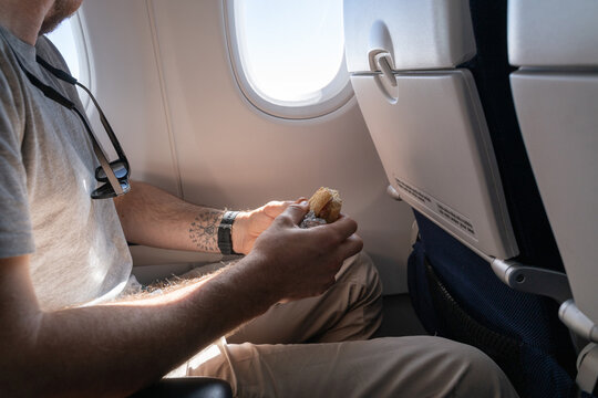 Man eating sandwich on plane