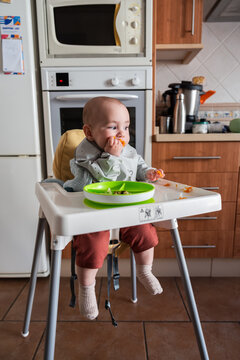 Baby eating peas in high chair