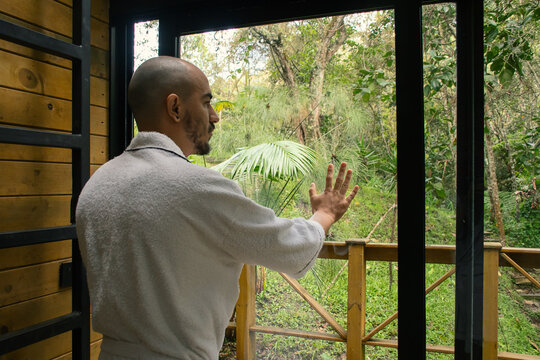 Man in a bathrobe opening a sliding glass door 