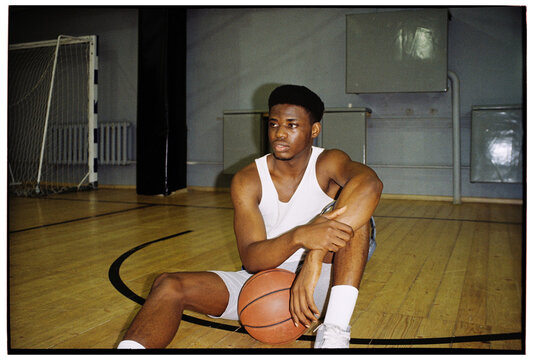 Basketball Player Resting on Court with Ball
