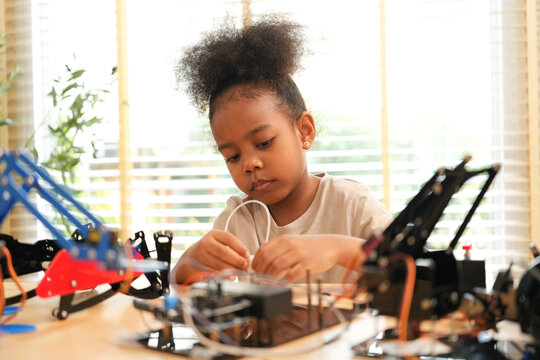 Focused young girl assembling components of a robotics kit at home. Concept of STEM education, early childhood development, and future technology skills.