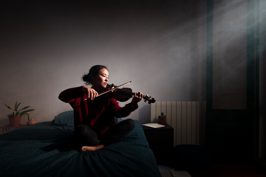 Cinematic portrait of violinist playing on bed