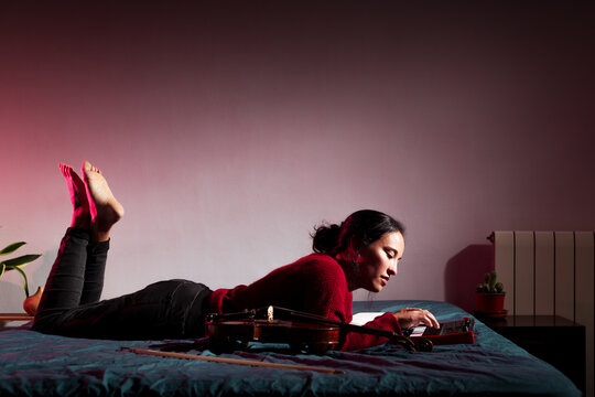 Relaxed woman composing music on bed