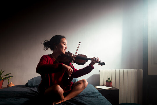 Happy violinist practicing on bed
