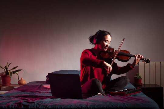 Smiling violinist student playing on bed