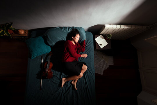 Tired musician resting on bed after creative process