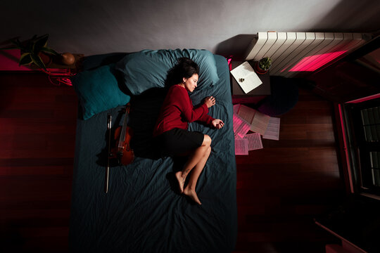 Relaxed woman lying on bed at cinematic bedroom 