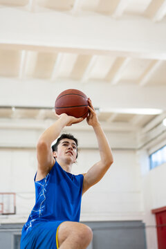 Young Man Shooting Basketball in Gym
