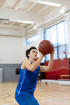 Young Man Shooting Basketball in Gym

