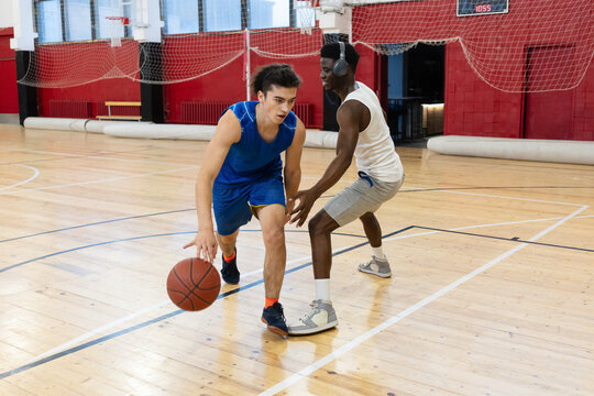 Two young men play basketball i, engaging in a one-on-one game