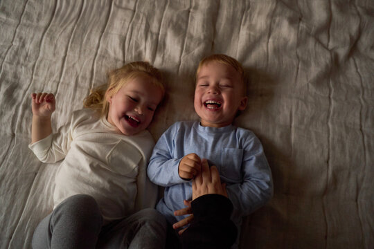 Kids laughing while being tickled on bed
