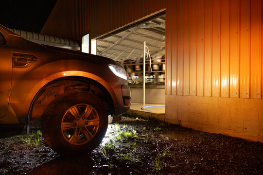 Pickup parked in front of open milking shed door.