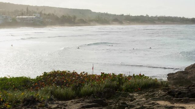 Looking at surfers on a rocky hill, on late afternoon at Jobos beach, Isabela, Puerto Rico.  