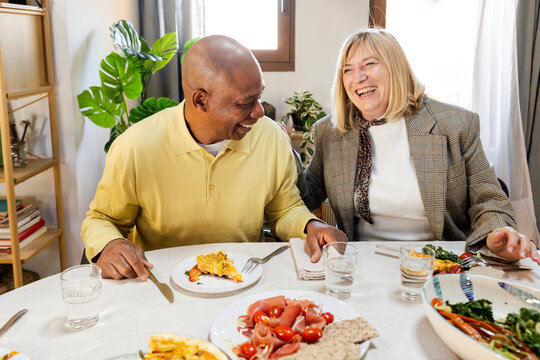 Senior couple laughing by dining table at friends gathering