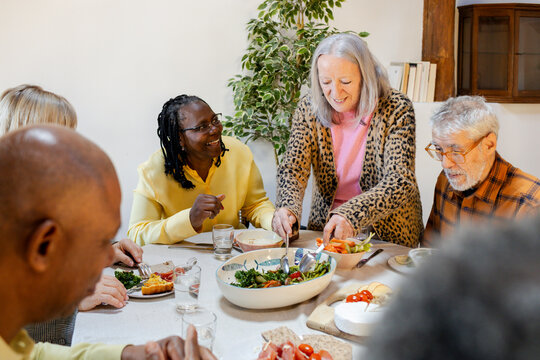 Party of senior friends reunited together around dining table