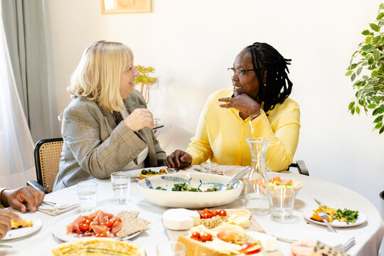 Two senior female friends having intimate conversation at lunch