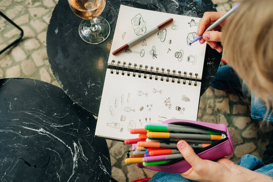Overhead view of woman sketching food doodles at cafe