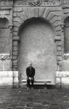 Man sitting alone on a stone bench