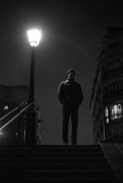 Silhouette of a man standing next to a city lamp, Paris