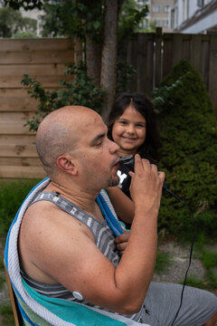 Daughter smiling watching her father trim his beard