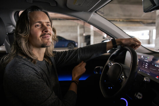 Man Inside Modern Car Smiling While Seated in a Parking Garage