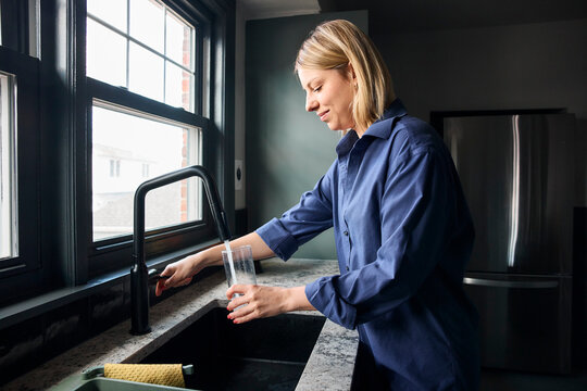 Young woman filling up a glass of water