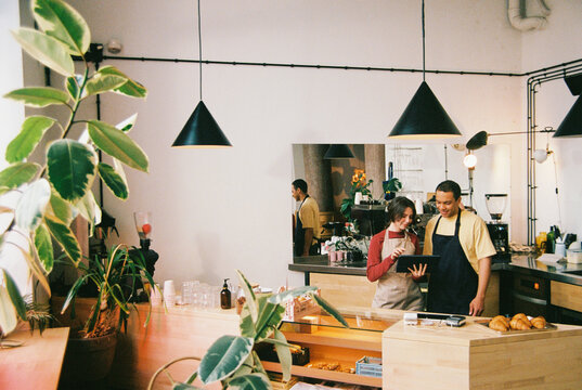 Film photo Small Business Owners Working With Tablet in Cozy Cafe