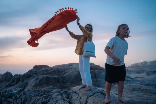 Shaking out towel on rocky beach at dusk