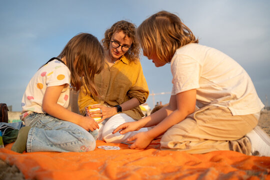 People playing card game on beach blanket