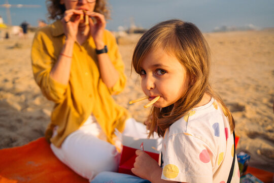 Girl with fries in mouth glancing at camera