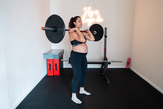 Pregnant athlete lifting weights in home gym: maintaining 