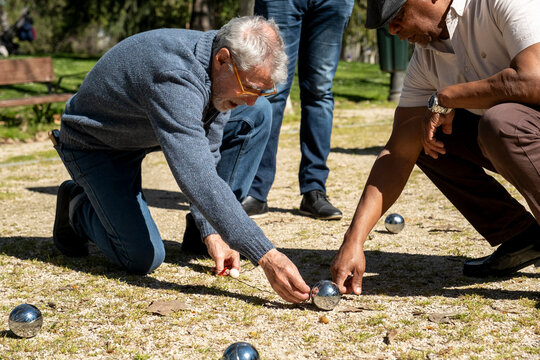 Senior friends playing bocce in park checking score