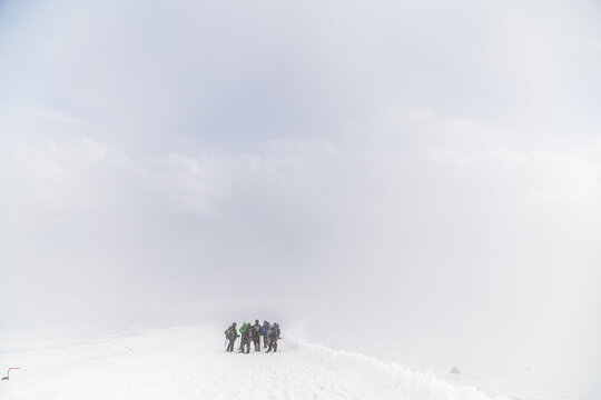 Group of hikers navigating through thick snow in foggy weather