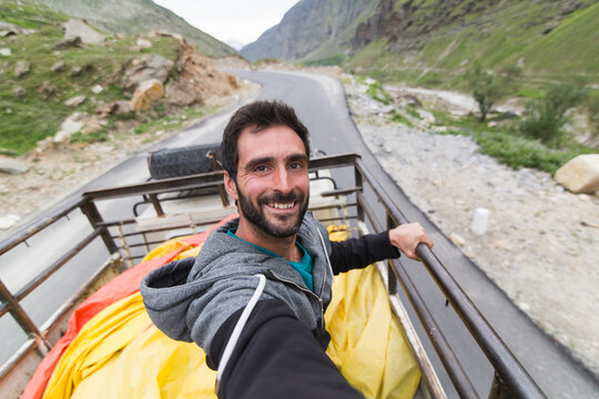 Traveler Selfie While Riding on the back of a Truck Through Mountains
