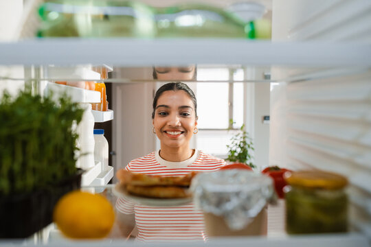 A woman takes food out of the refrigerator