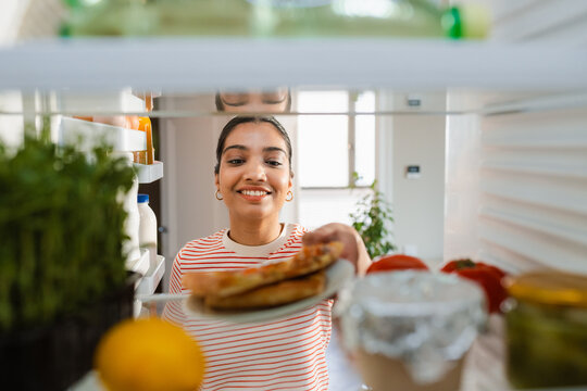 A woman takes food out of the refrigerator