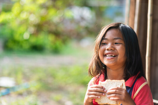 Smiling girl eating bread in rural Thailand