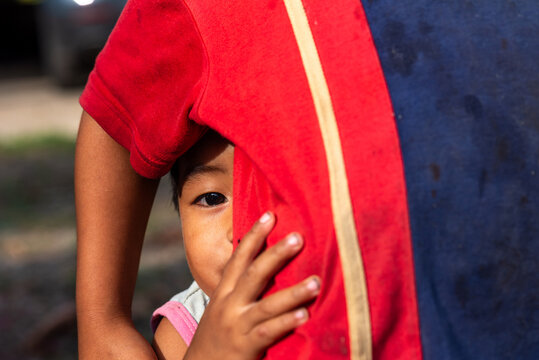 Young boy hiding behind his sister in rural Thailand