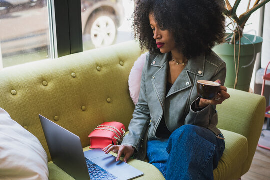 Woman Working on Laptop While Holding a Coffee Cup 