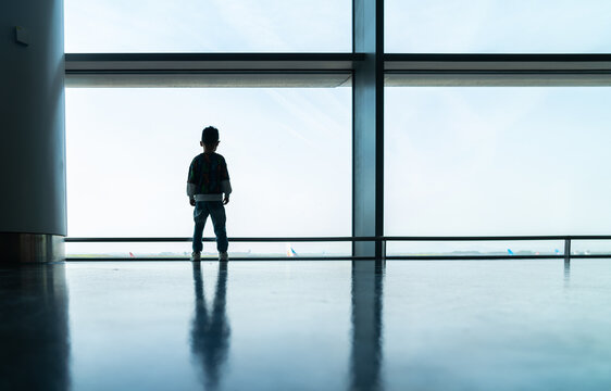 Boy standing by airport window