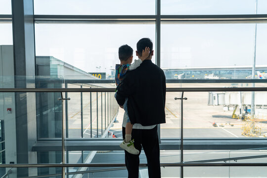 Man holding son watching planes at airport
