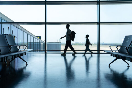 Silhouette of father and son walking at airport window