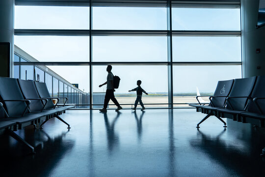 Silhouette of father and son walking at airport window