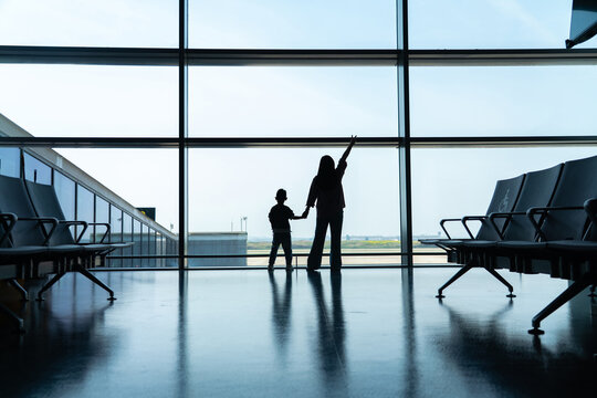 Silhouette of mother and son at airport window