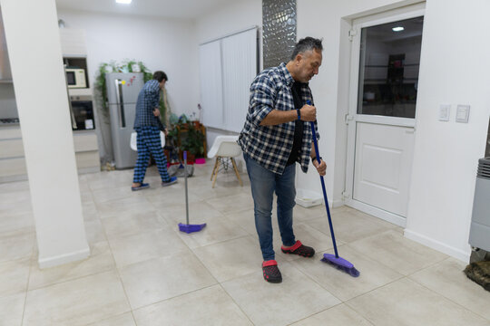 Men mopping a kitchen floor together at home