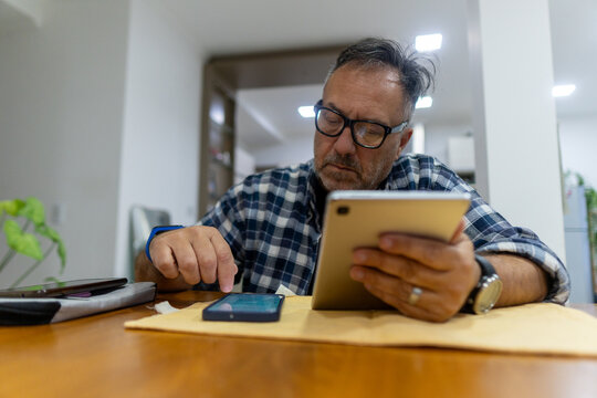 Focused Man Using Tablet and Smartphone at Home