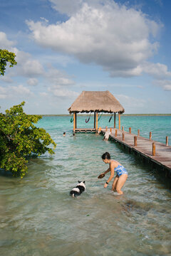 Woman at Bacalar Lagoon playing with her Border Collie dog 