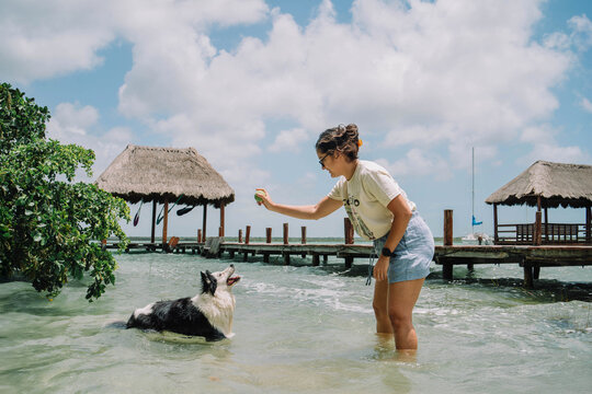 Latina woman playing on a lagoon with her border collie.